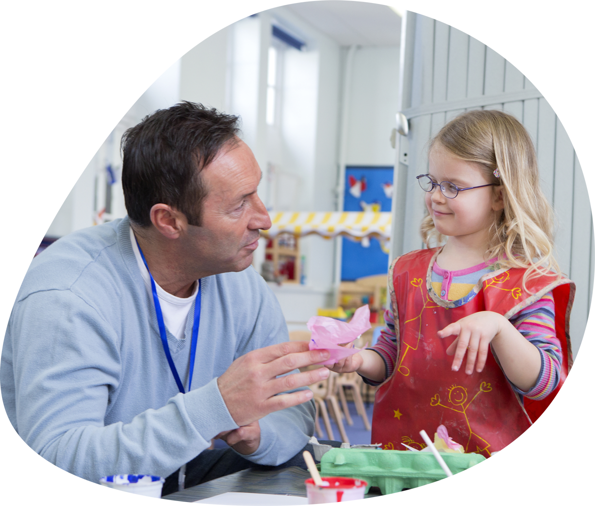 Childcare teacher showing arts and crafts to a student