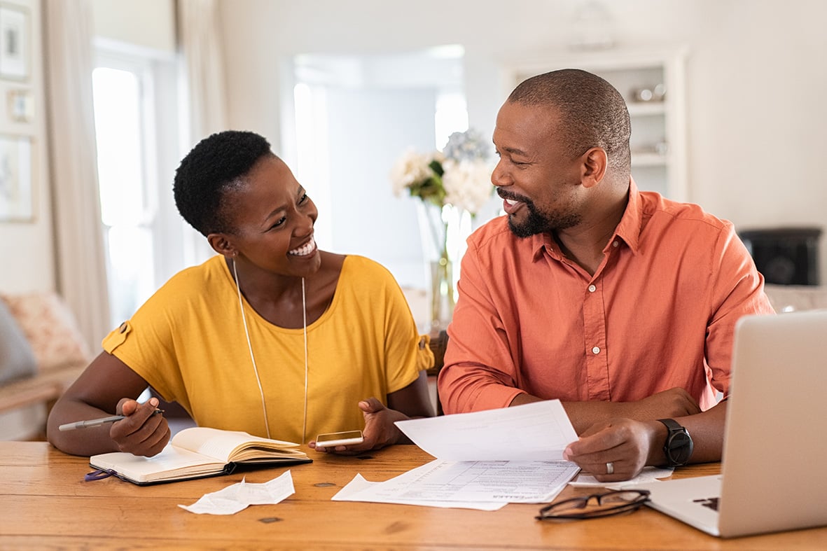 Cheerful black man and woman planning on a wooden table.
