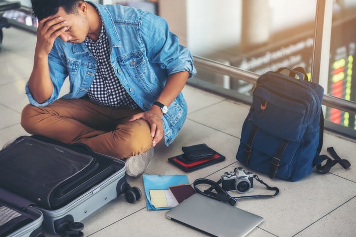 An Asian male traveler is experiencing the problem of need and lost value at the airport, lost electronics, lost laptop, lost phone, lost tablet