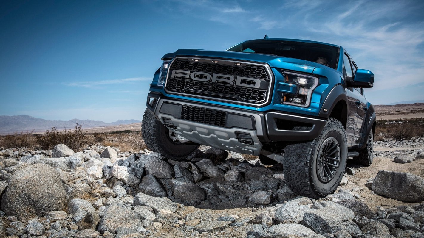A Ford automobile in blue and black is parked on the rocks.