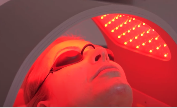 Woman wearing goggles lying under red-light canopy