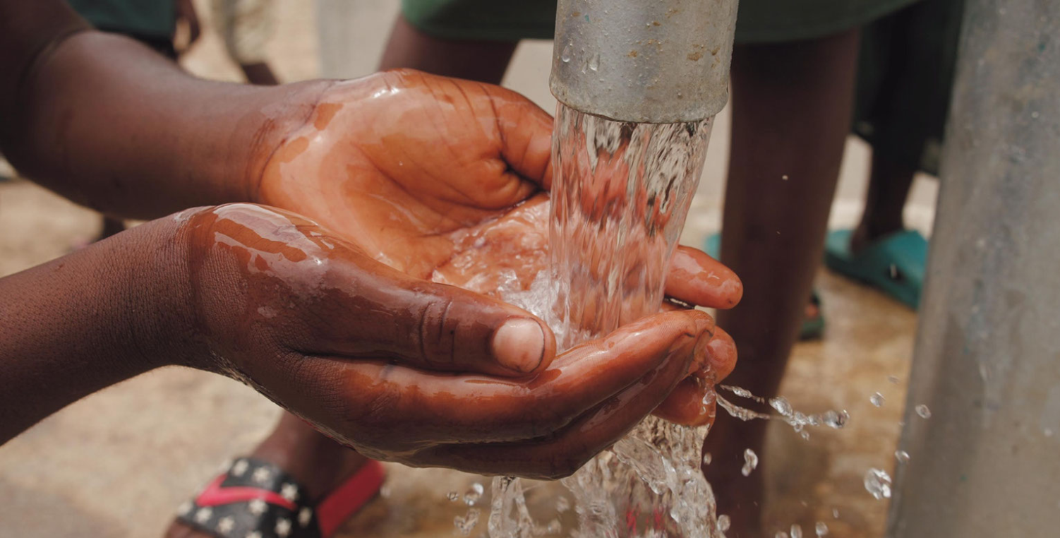 hands cupping water from water pump