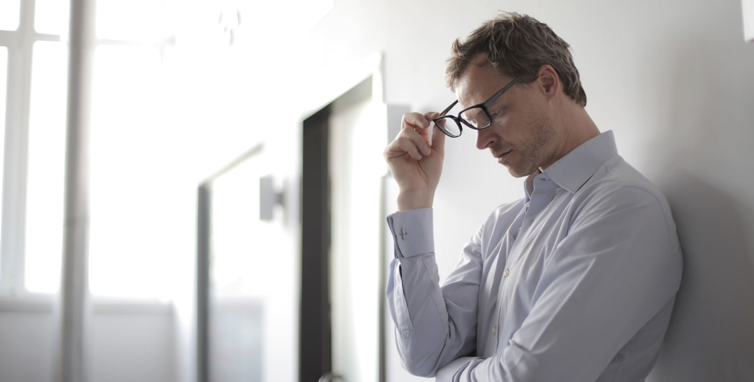 stressed out man leaning against wall