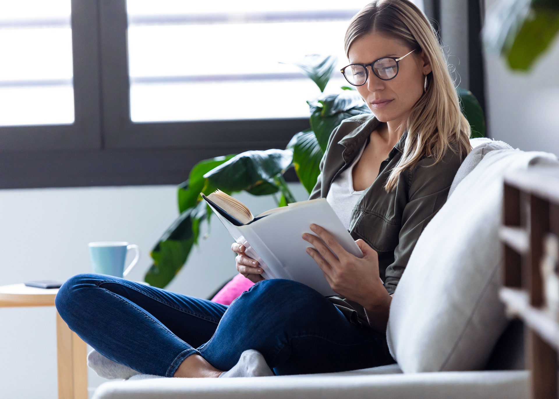 young-woman-reading-a-book-while-sitting-on-couch
