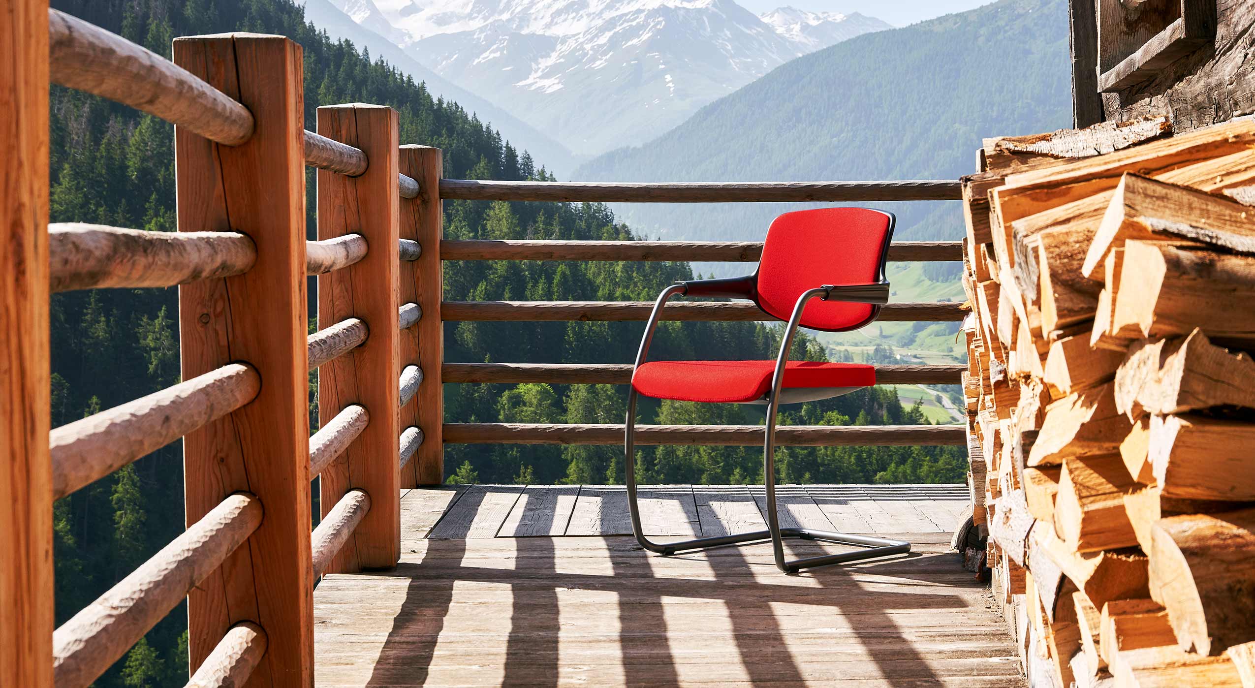 Red giroflex 161 visitor chair on a wooden balcony in the Swiss mountains