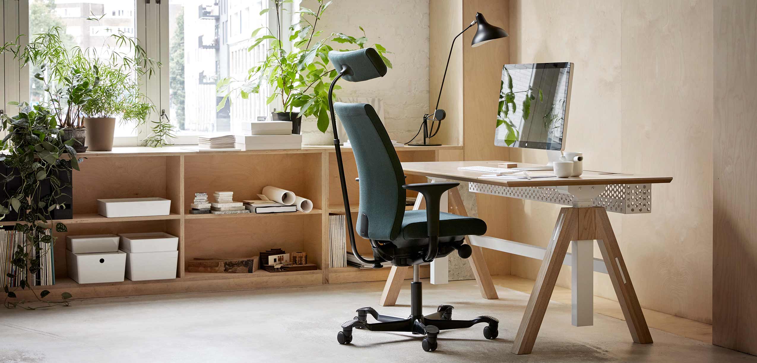 dark green HÅG Creed chair at a wooden height adjustable desk with an apple mac on it in a light office