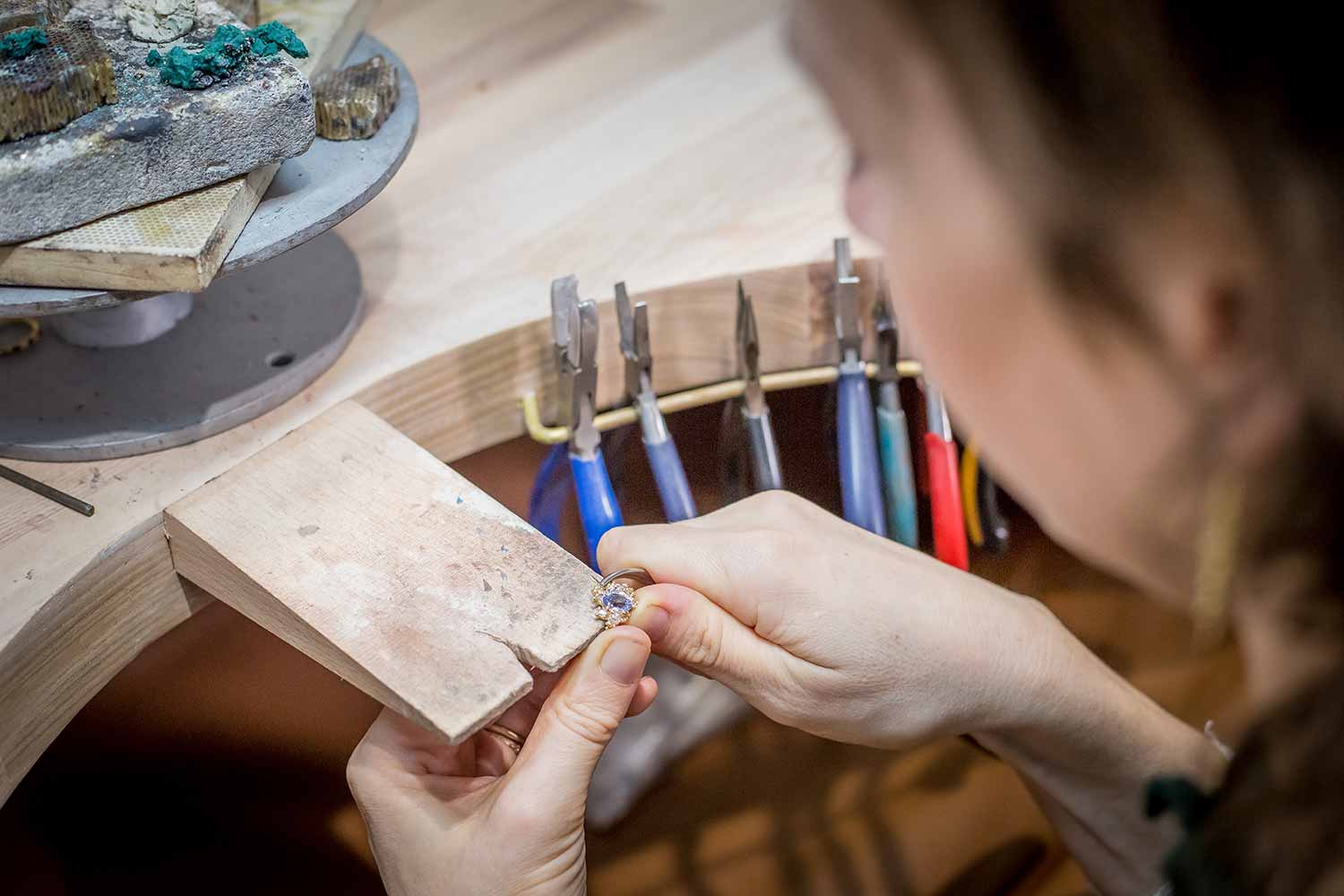 close up of jeweller Ruth Tomlinson working on a piece of jewellery with her hands on a wooden clamp