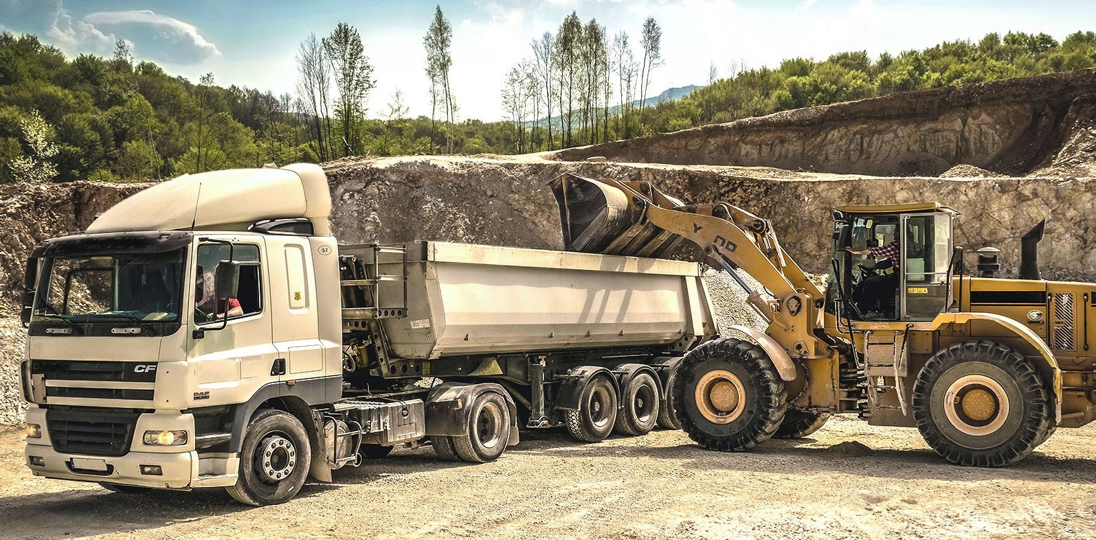 annata-front-loader-filling-a-tractor-trailer-against-a-quarry-background