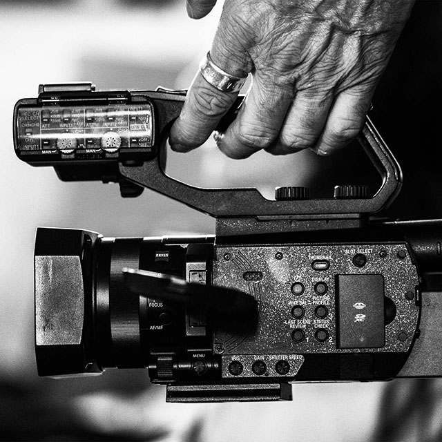 Black and white image of a hand holding a video camera
