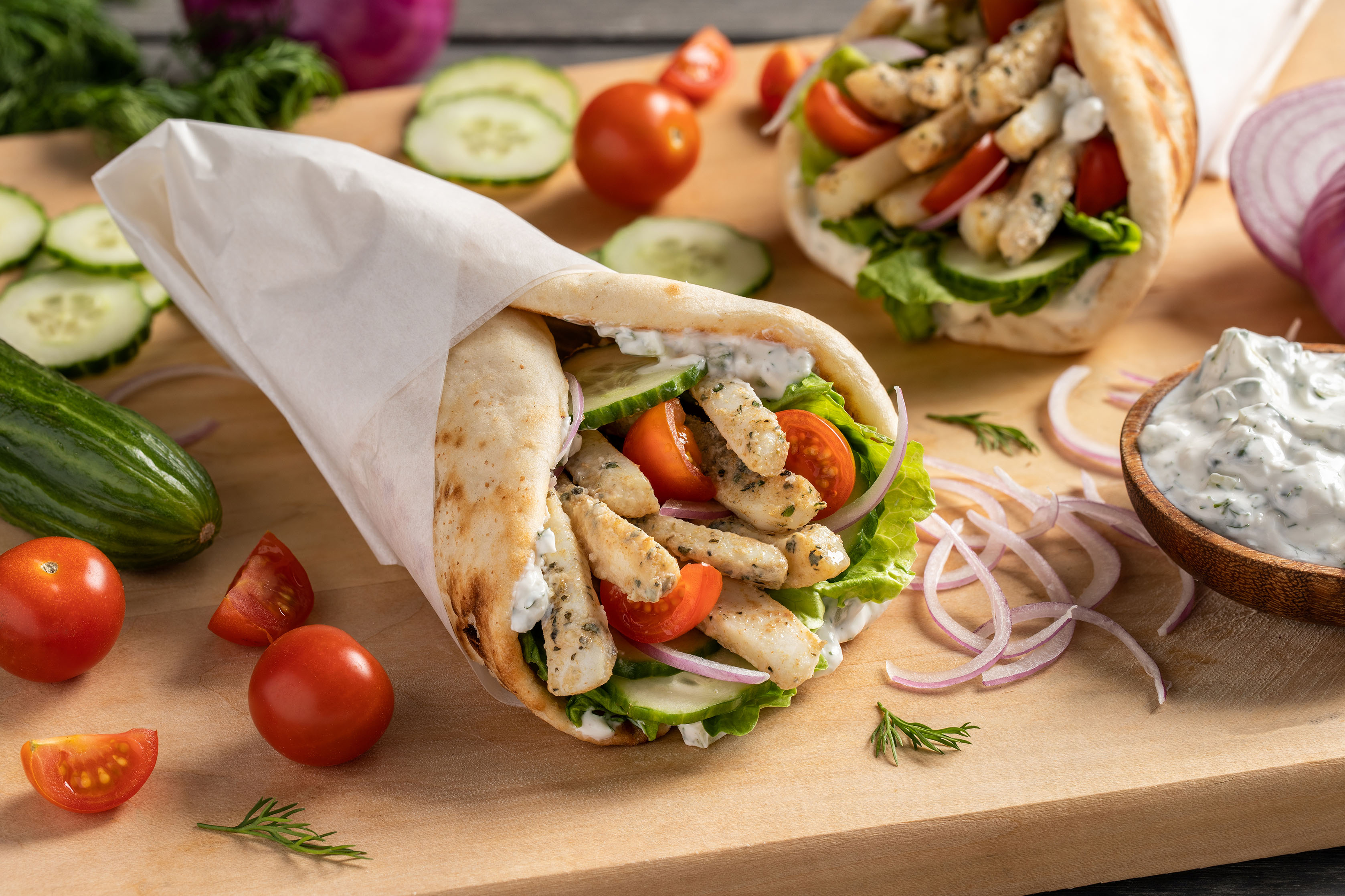 A gyro wrap with calamari strips, lettuce, tomato, and tzatziki