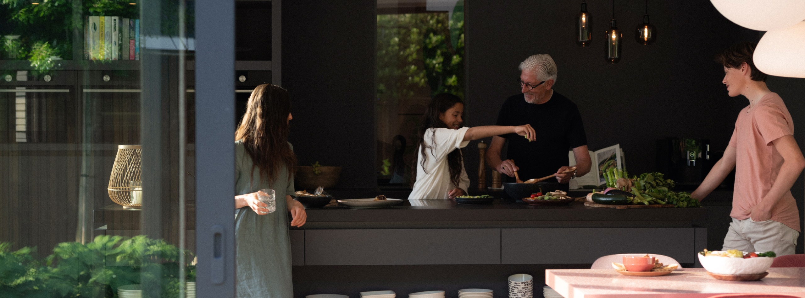 Hero binnenzwembad familie binnen eten aan het maken in donkere keuken