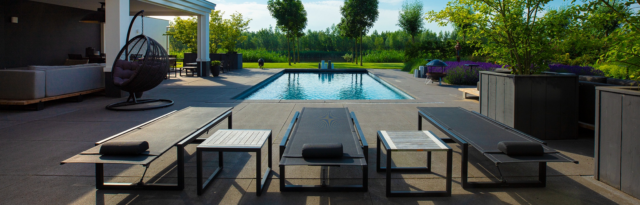 Luxe maatwerk zwembad in een tuin met grote grijze tegels en een modern ontwerp