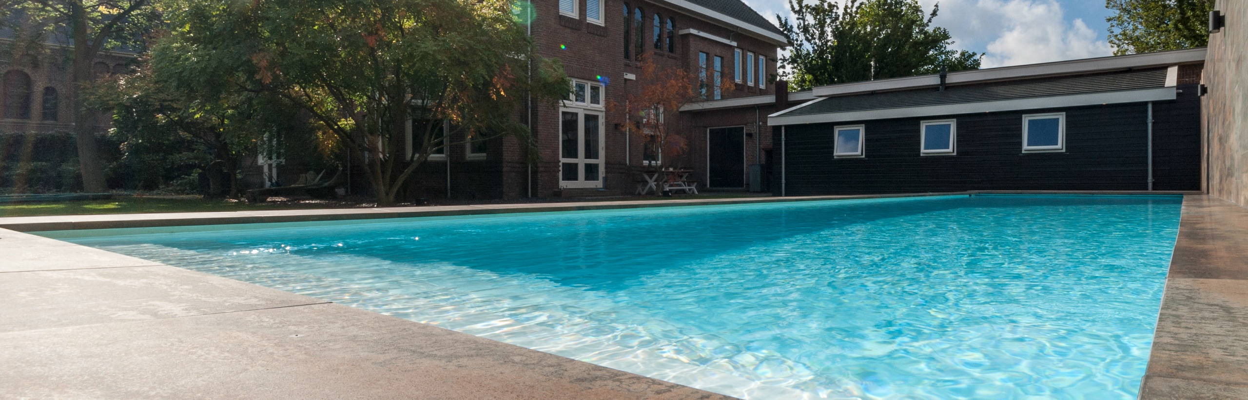 Zwembad met hoge waterlijn en natuursteen terras