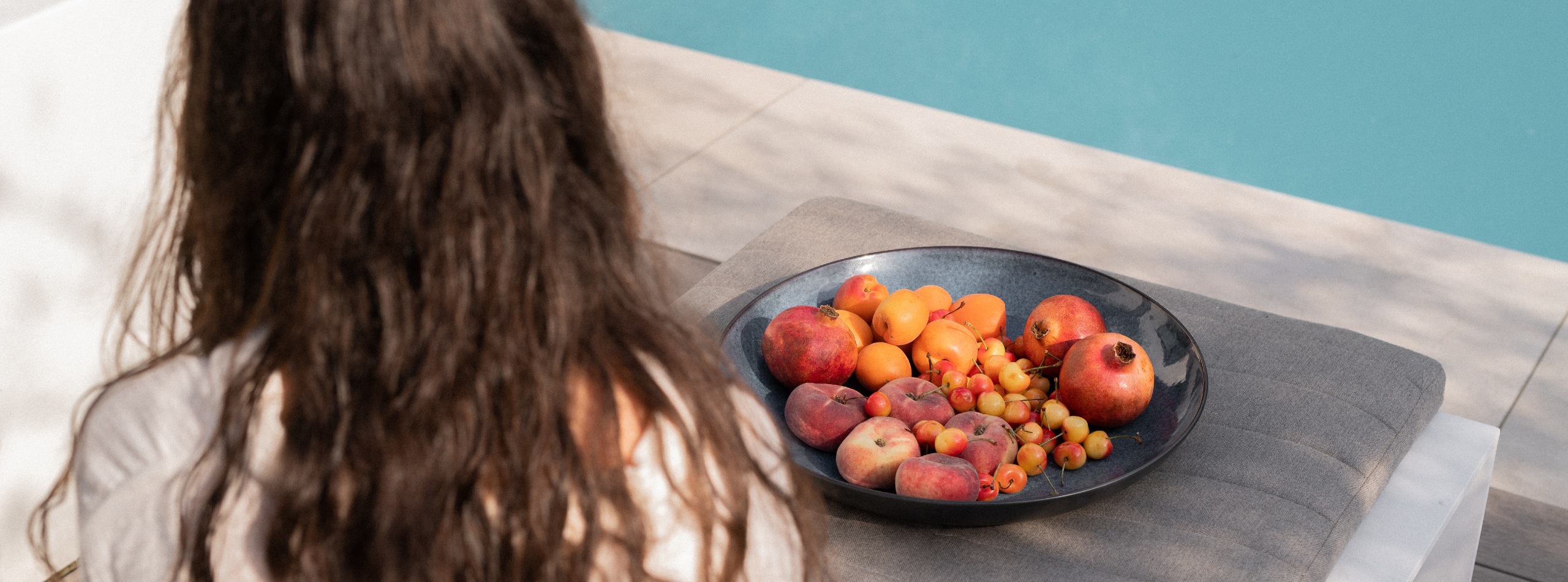 Hero plunge pool meisje op ligbed bij inbouwzwembad met fruitschaal