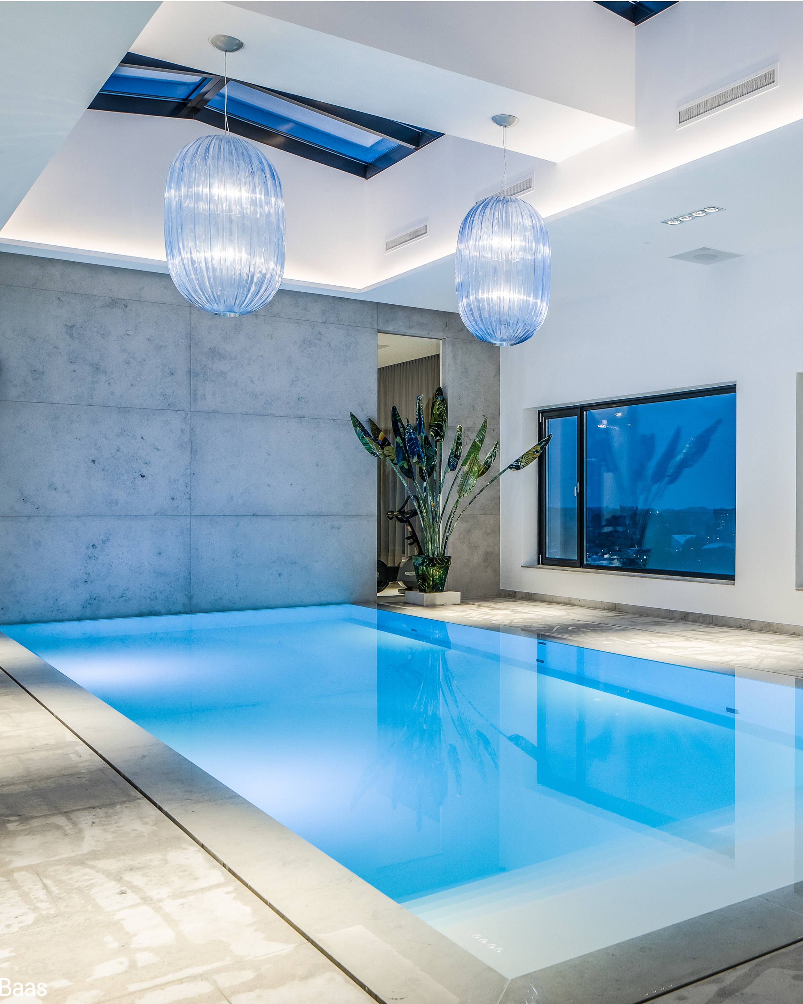 Overloopzwembad binnen infinity pool van starline met hoog plafond hanglampen strakke waterlijn
