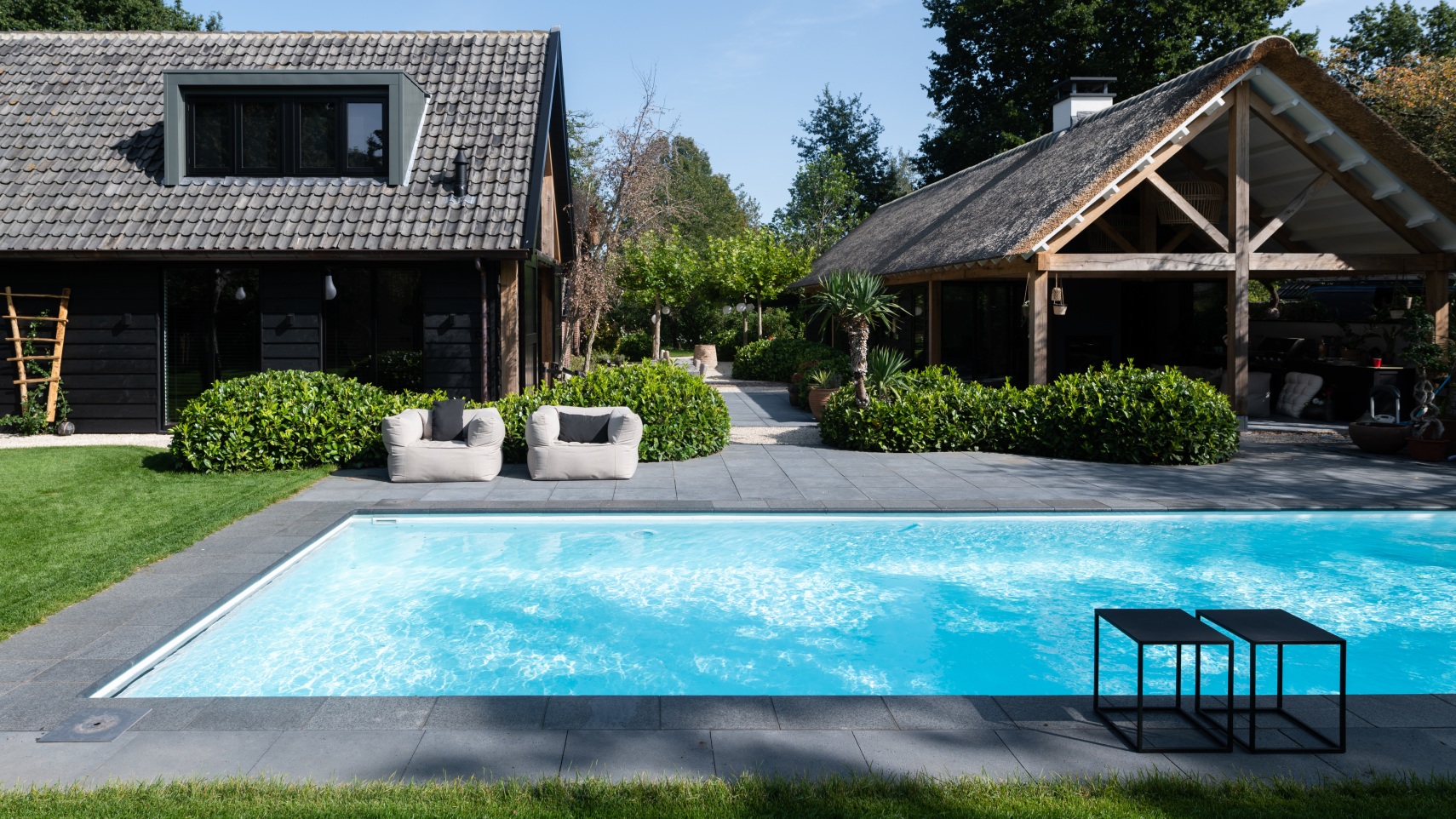 Polypropyleen skimmerzwembad buiten op zomerse dag met veel groen eromheen en een riant poolhouse