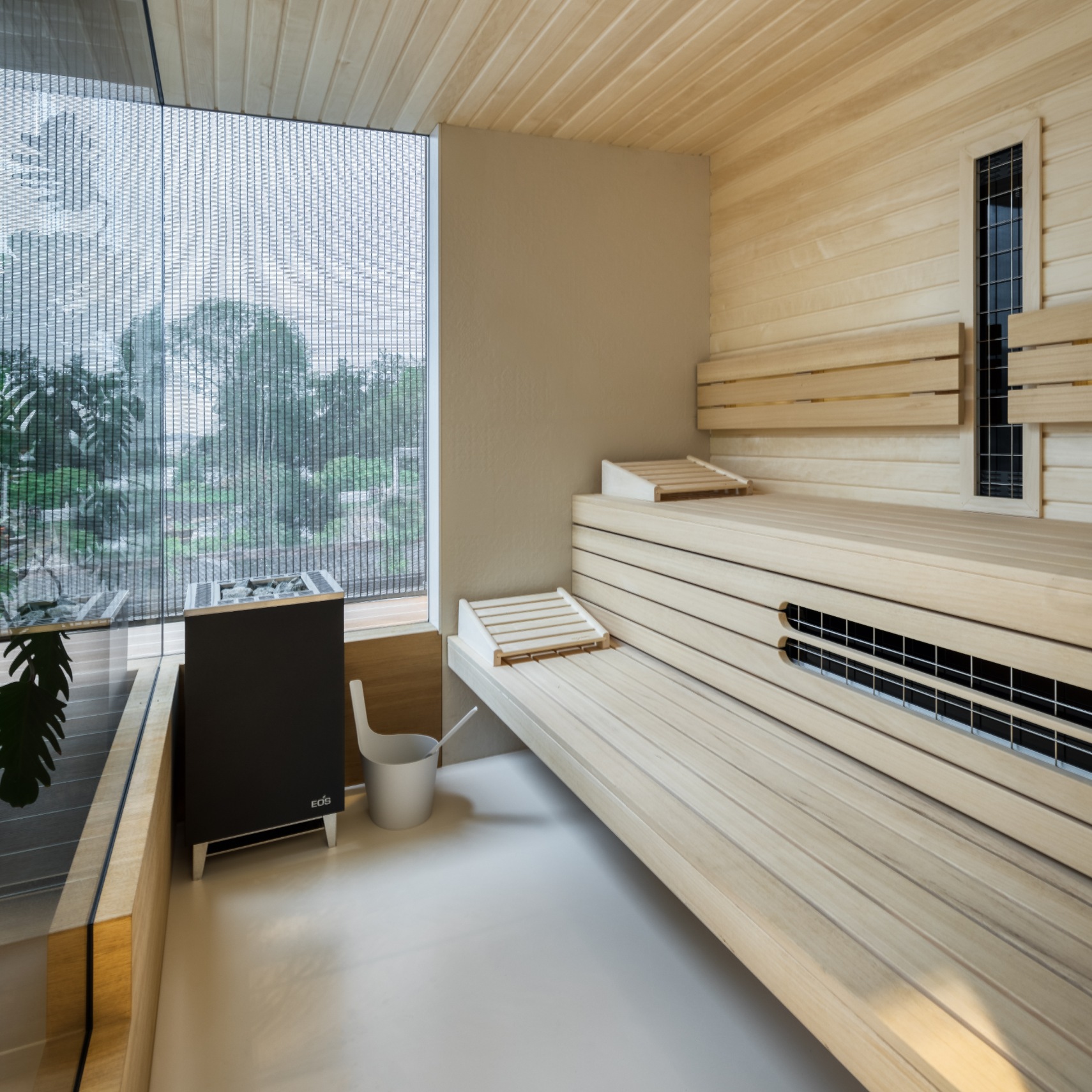 Sauna op maat met licht hout en een kachel en infrarood met grote glaswand en betonvloer