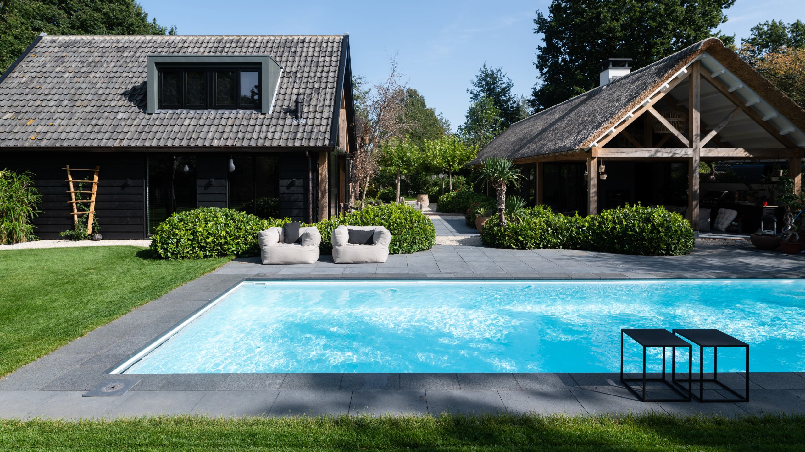Zwembadbouwer die een inbouwzwembad op maat in een tuin met houten schuur