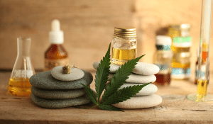 Cannabis-Image of a cannabis leaf, oils, and stacked rocks in a spa-like theme