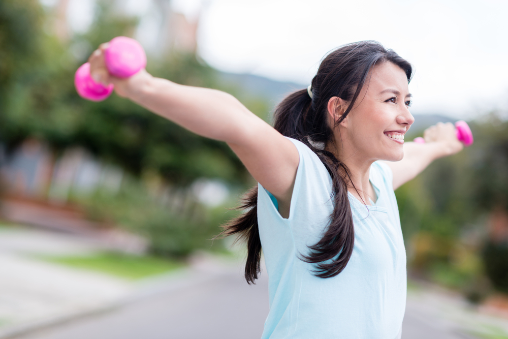 Excited woman training outdoors with arms up looking very happy