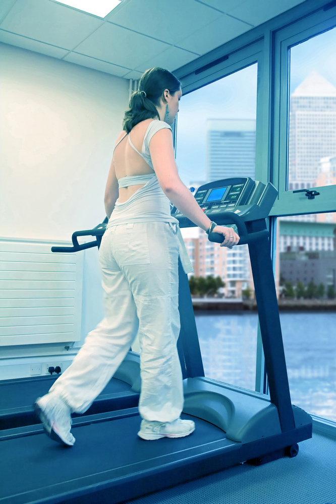 beautiful woman running on a treadmil dressed in white