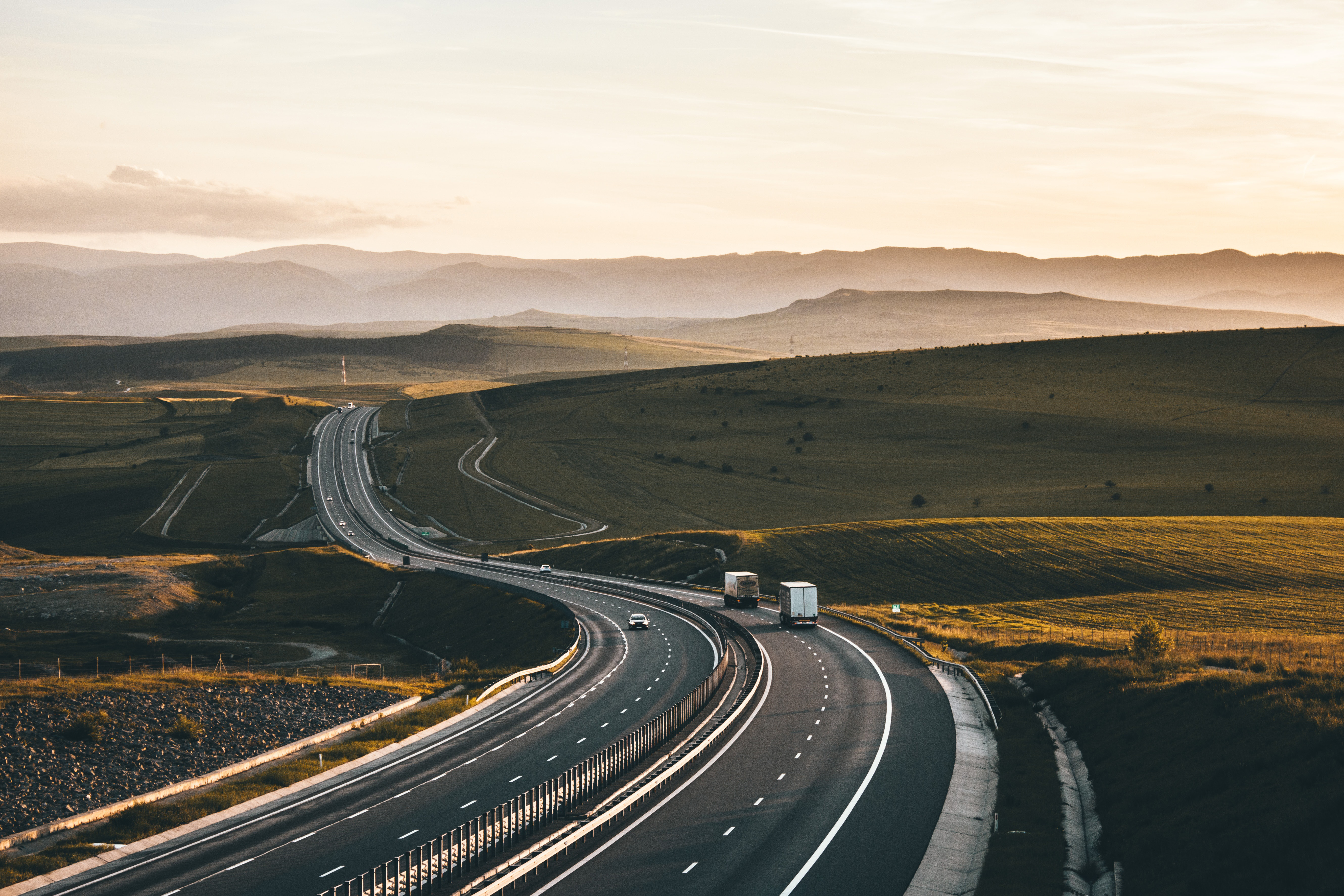 Fotografía de una larga carretera de montaña con camiones pesados.