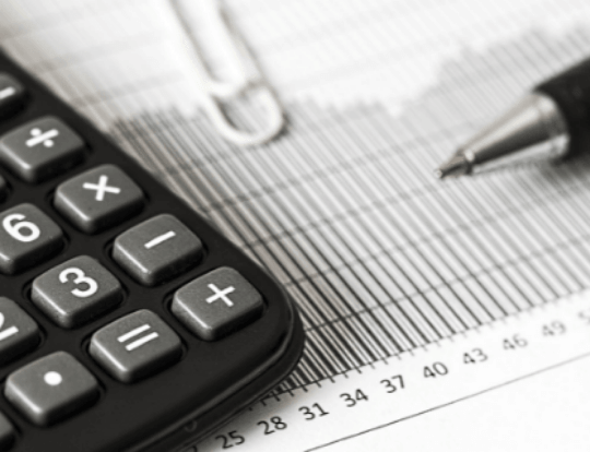 Photographie d'une calculatrice et d'un stylo posés sur un document financier.