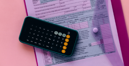 Fotografia de uma calculadora em cima de documentos financeiros.