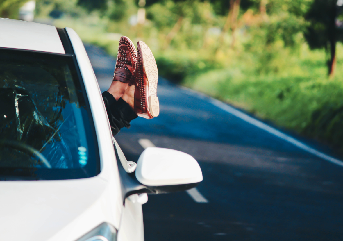 Personne qui sort ses pieds par la fenêtre de sa voiture