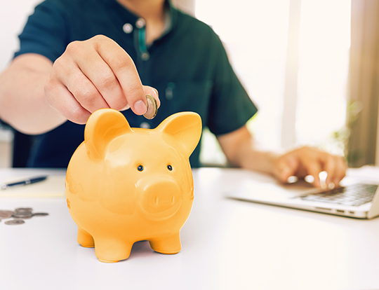 Man who works and adds a coin to his piggy bank